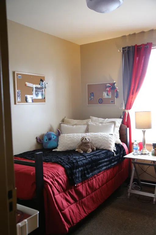 Interior of a dorm room with a twin bed and window.