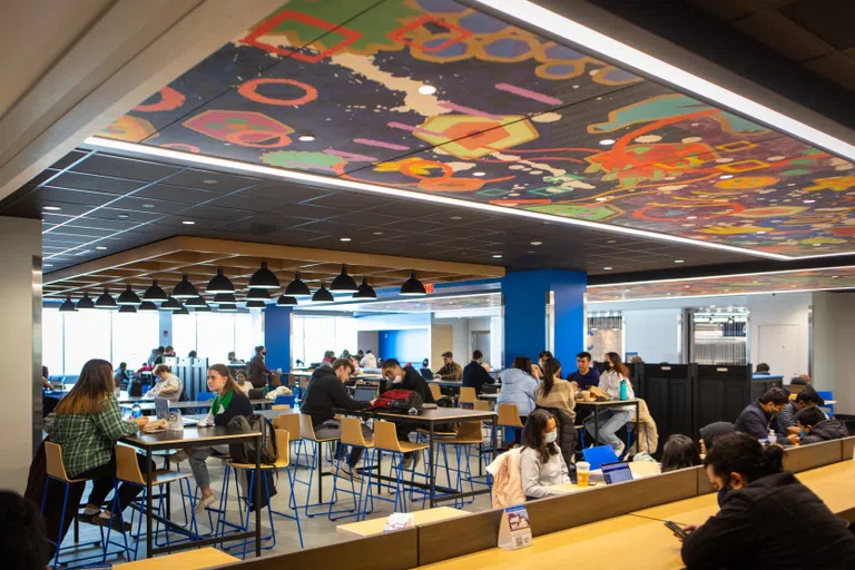 Students sitting in One World Café under artist mural.