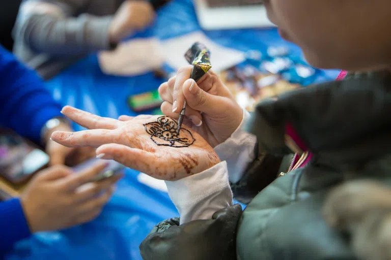 Photo of students drawing henna at the World Bazaar.