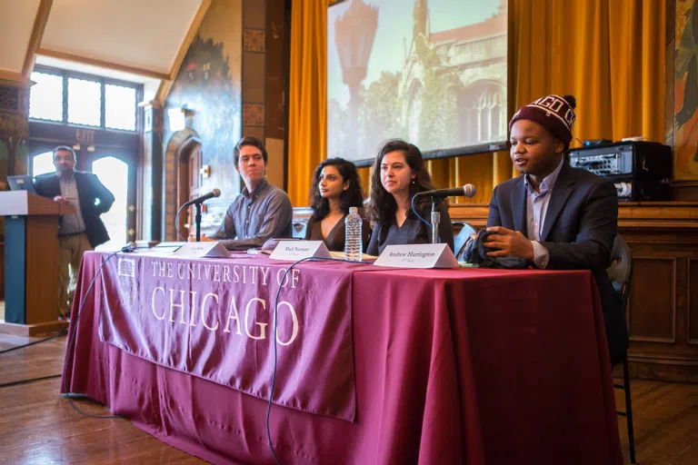 4 students sit at a table with a maroon tablecloth