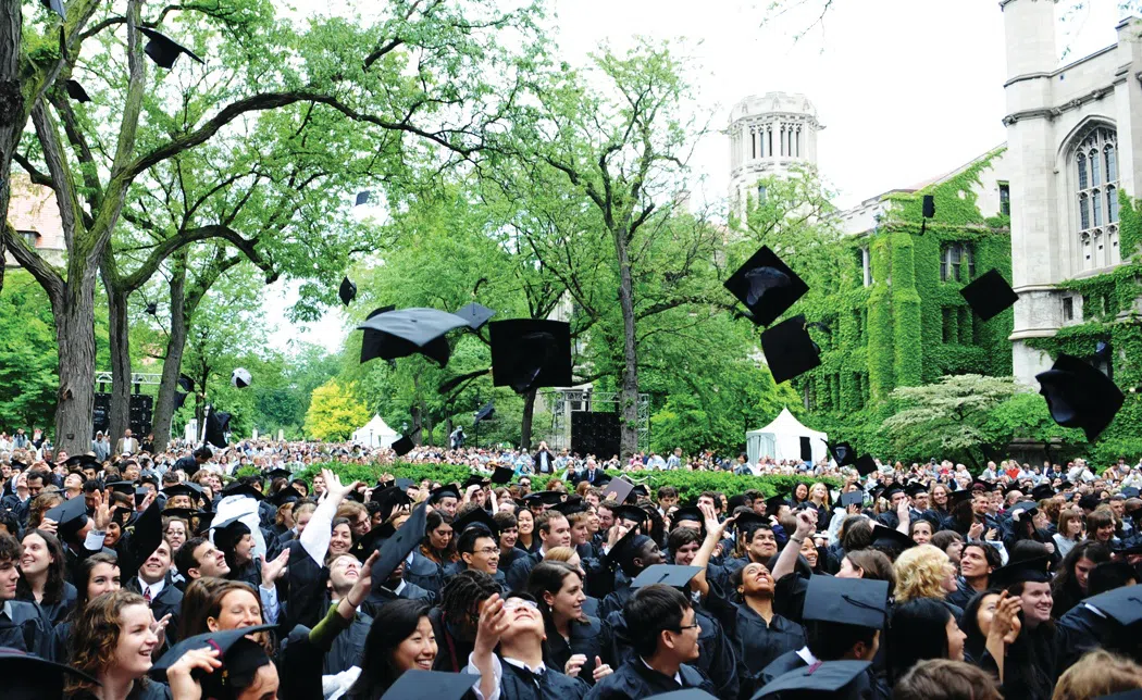 Students in cap and gown on the main quad throwing caps at graduation