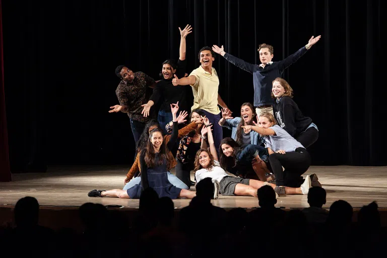 A group of 11 students stand on stage in a finale pose