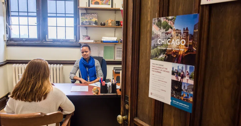 A student talks to an adviser in an office with an open door