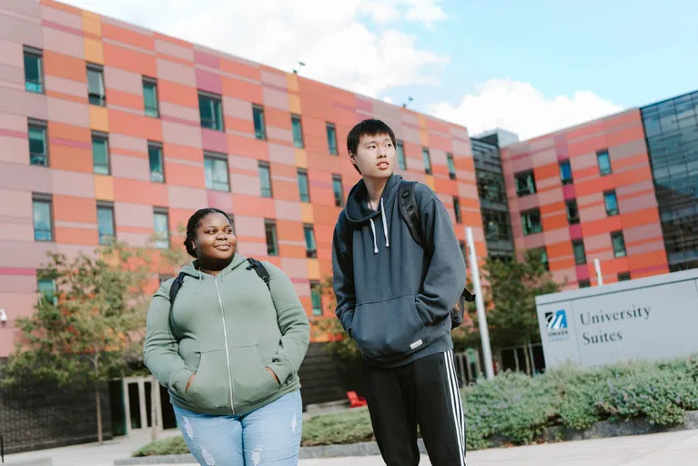 Female and male students outside University Suites at UMass Lowell