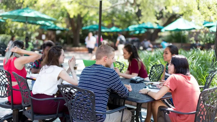 Students sitting together on patio furniture, outside of the Russell House