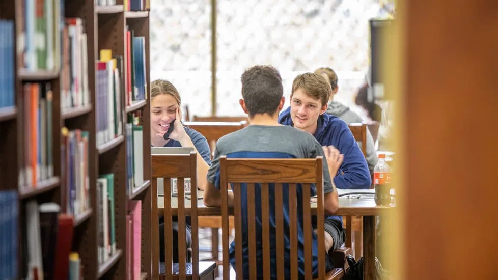 Three students work in a small group on the main floor of Thomas Cooper Library.