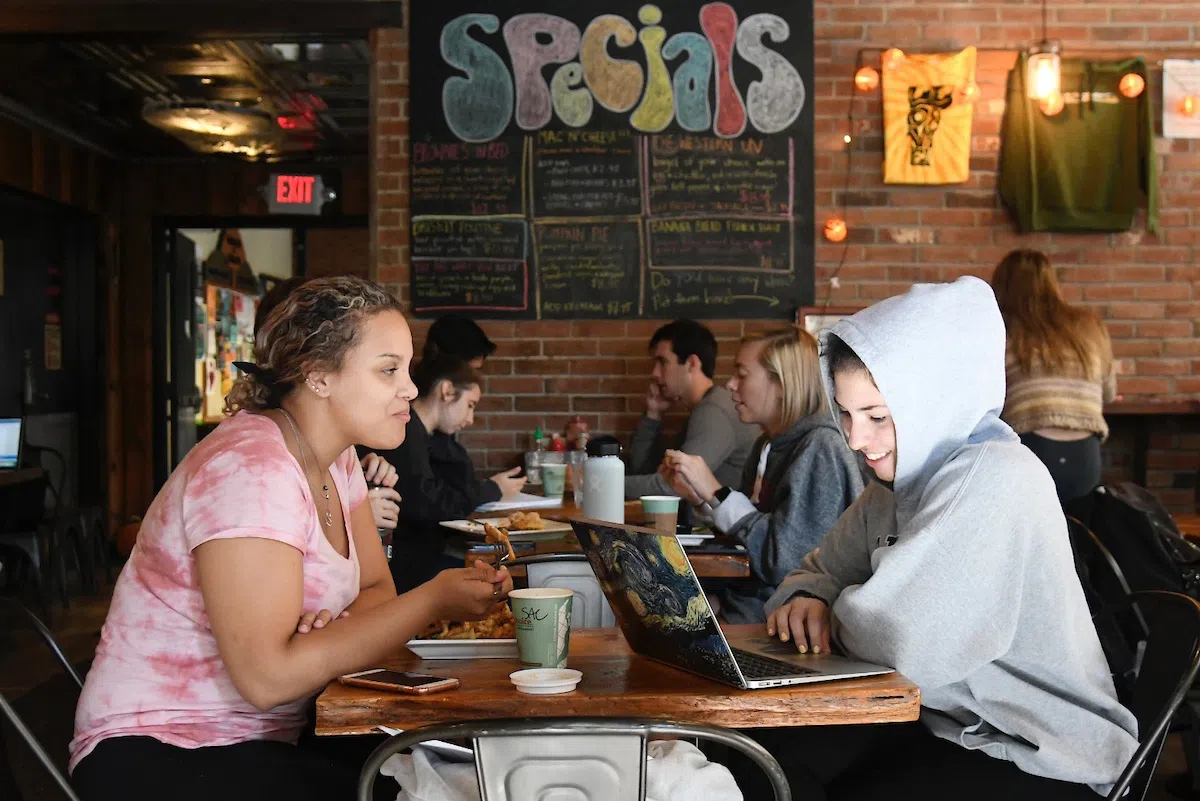 Two students facing each other sitting at a restaurant table.