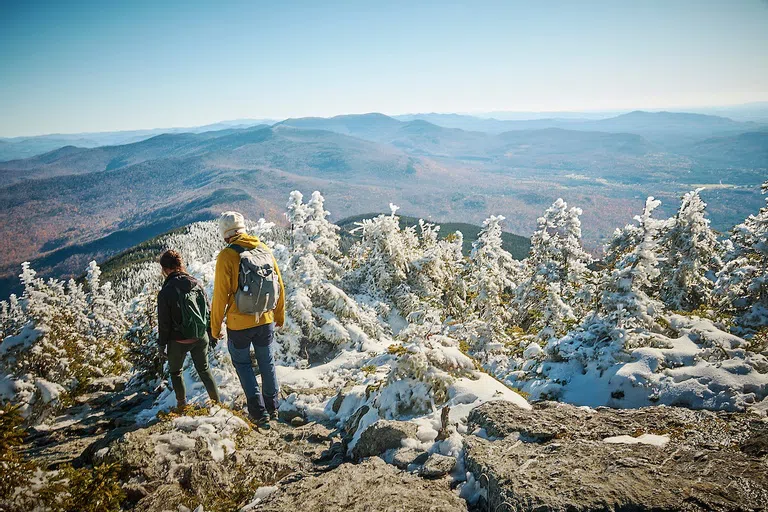 Two people on a mountain top with snow.