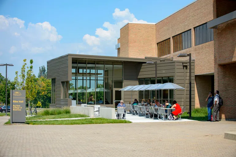 The photo shows the outside of Rike Hall including the outdoor seating area of the ReyRey Cafe.