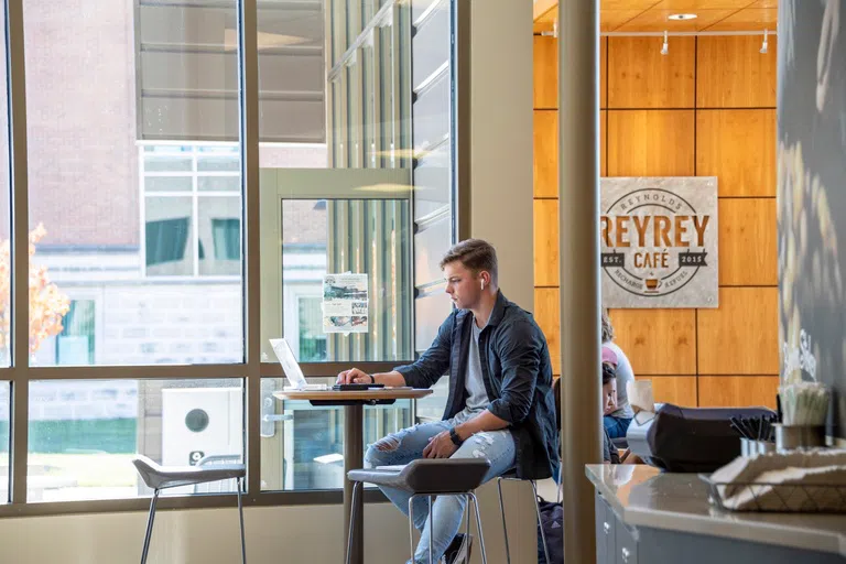 A student working on laptop in the ReyRey Café.