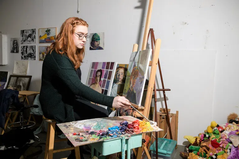 A student paints on a canvas in an art studio in the Creative Arts Center.