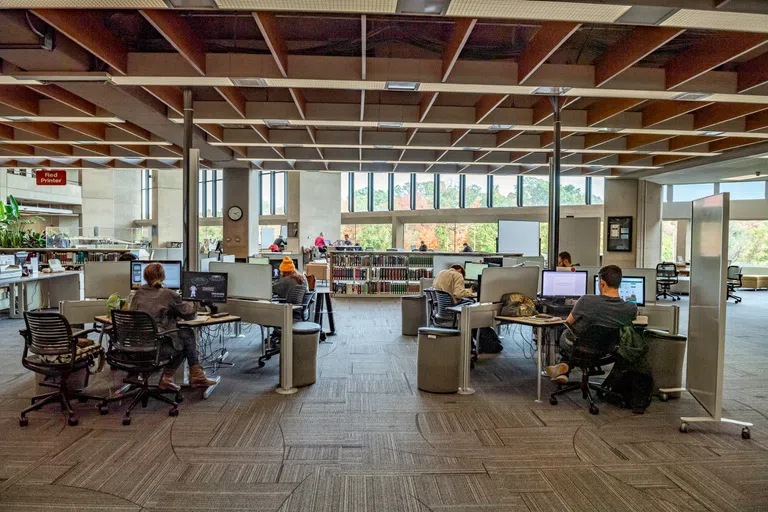 Students work at desk spaces with computers in the library.