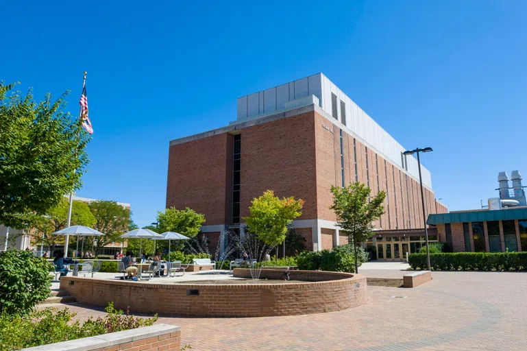 The Quad outside Oelman Hall and a water fountain with students sitting at tables and working outside.