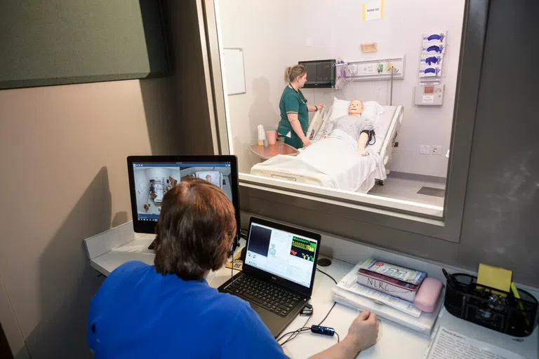 Nursing student practicing skills on patient simulator. 