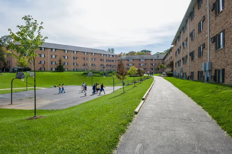 Students play basketball on outdoor courts near campus housing.