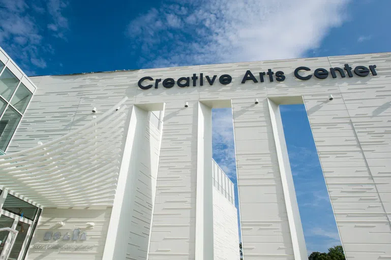 The front of the Creative Arts Center, a white building with textured blocks and windows. 