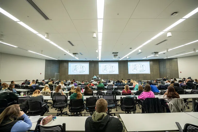 Students watch a lecture in classroom inside the Student Success Center.