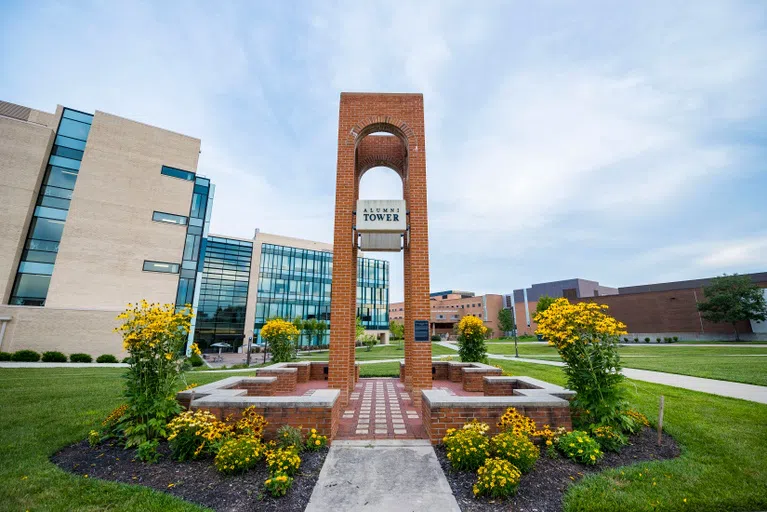 The Alumni Tower outside the Russ Engineering Center.  Flowers surround the tower.