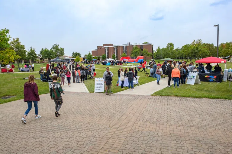 Students exploring different booths and activities on the lawn at the center of campus.