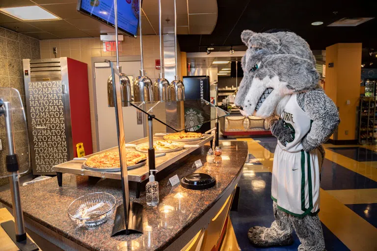 Rowdy stands in front of pizza options in the Union Market dining area.