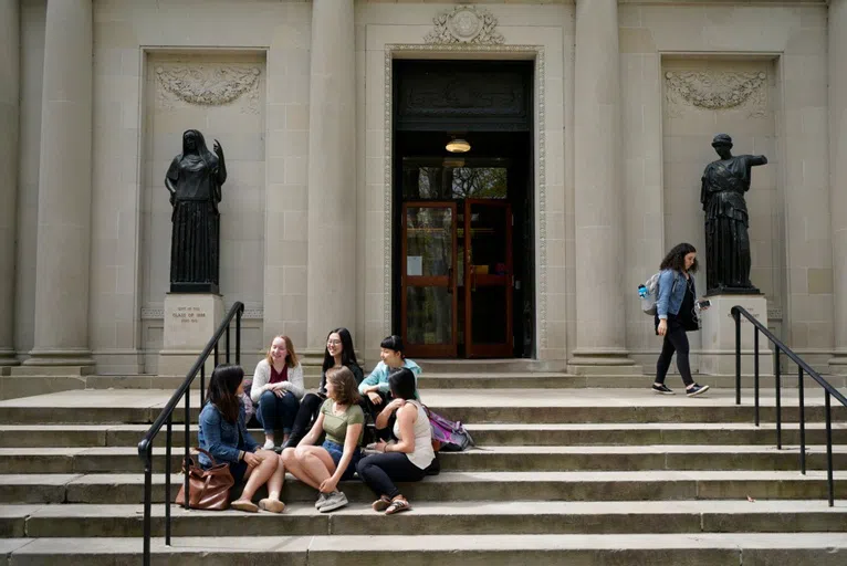 Wellesley students sitting on the steps of Clapp Library. 