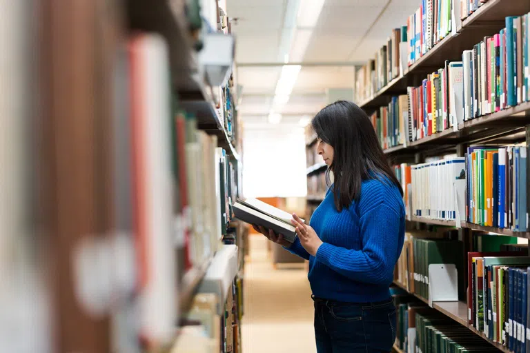 Wellesley student looking for a book in the Clapp Library stacks