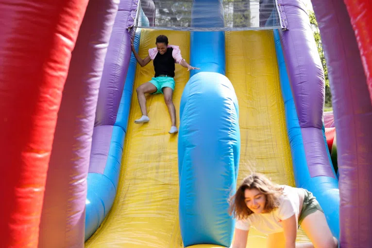 Wellesley students sliding down a bouncy slide during a Last Day of Classes celebration