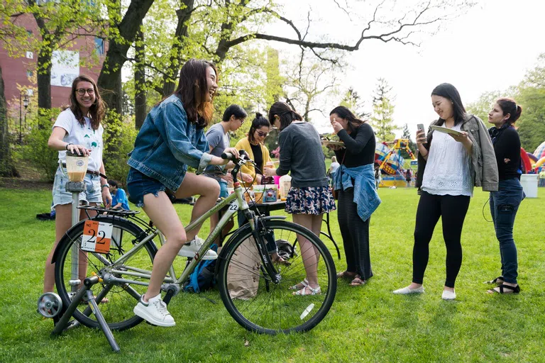 Wellesley student riding a smoothie bike during a Last Day of Classes celebration