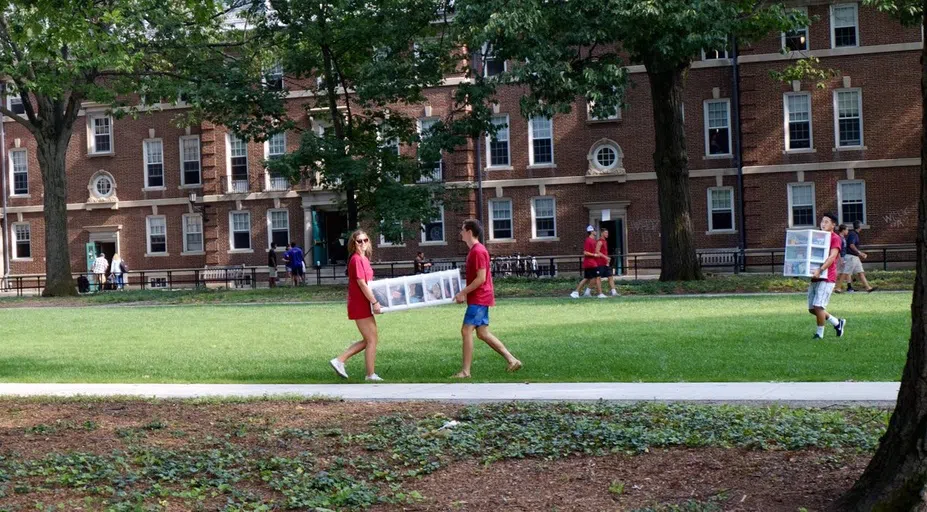 students carrying furniture across the grass lawn of Frosh Quad