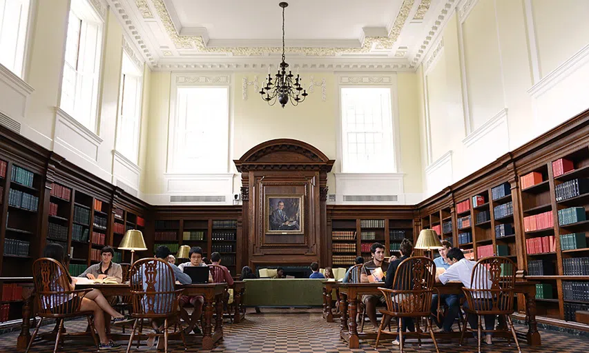 wooden library space with dark wood chairs and tables, and a centerpiece painting in the background