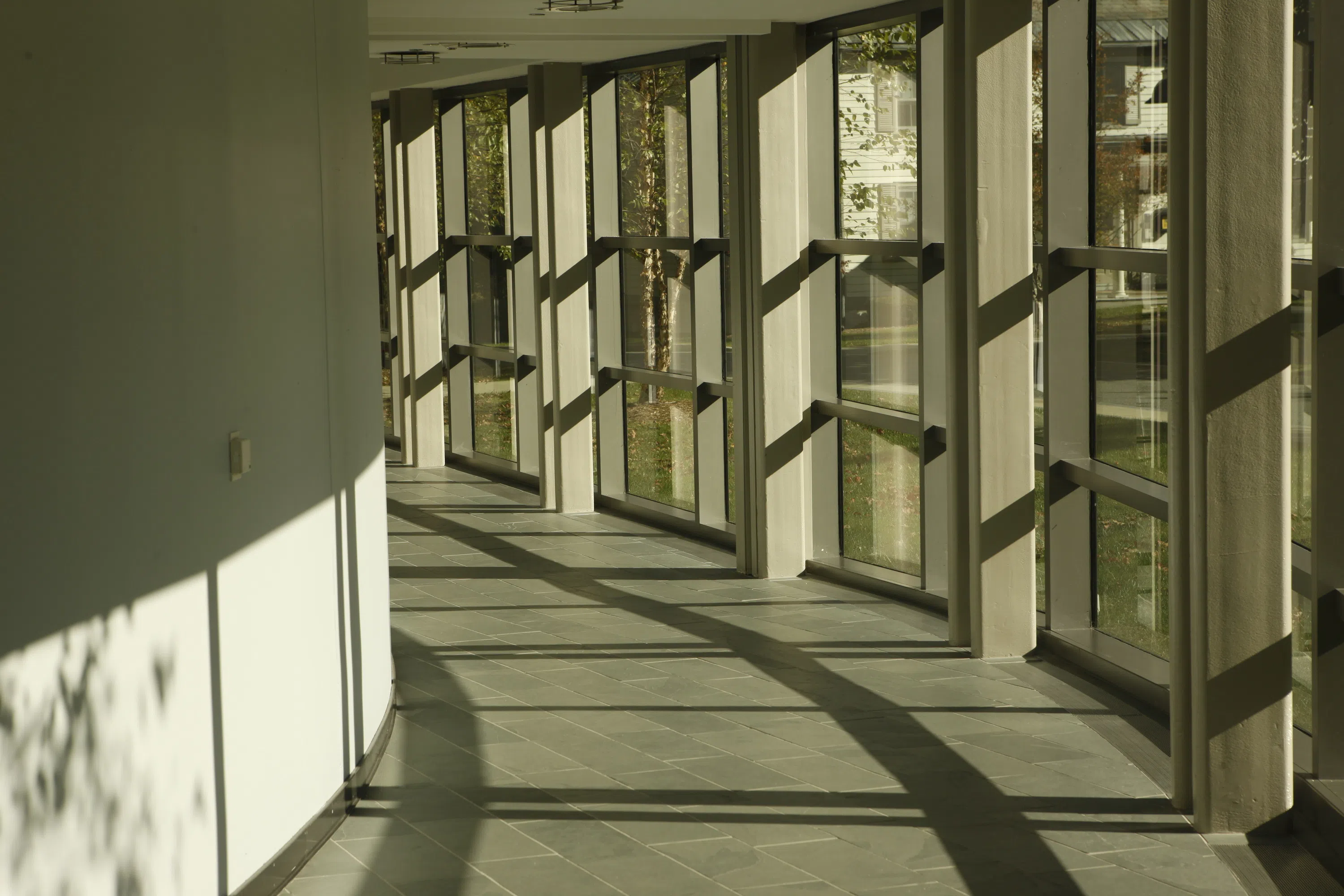 a rounded hallway with natural light coming through the glass walls