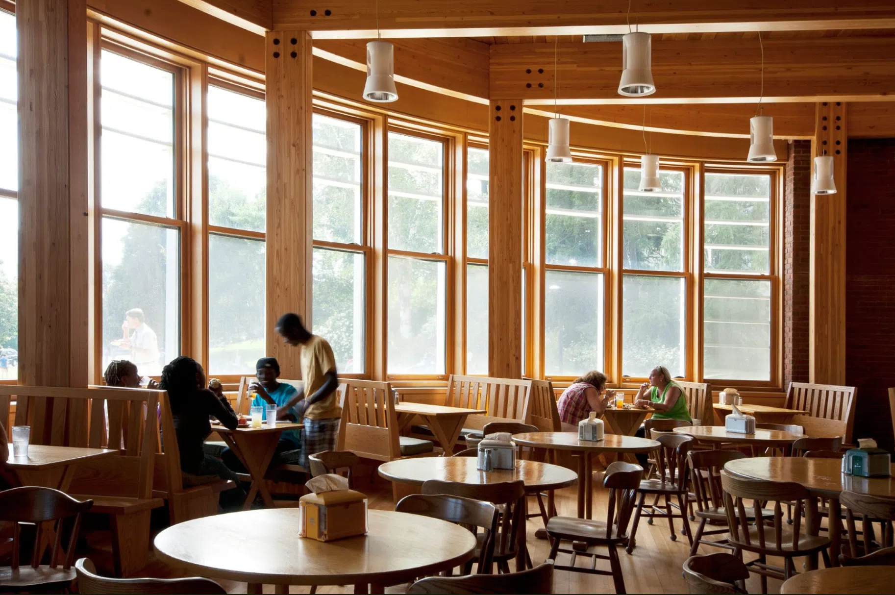 eating area with wood tables in an open round room with large windows