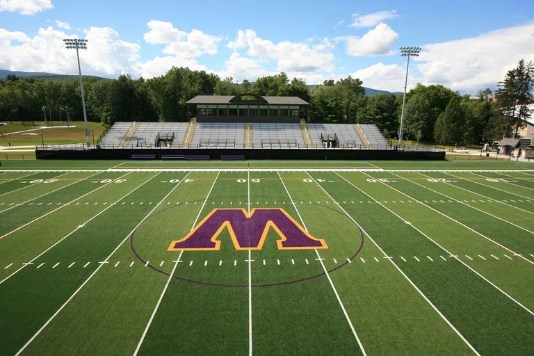 photo of Weston field with the purple Williams "W" and bleachers and trees in the background