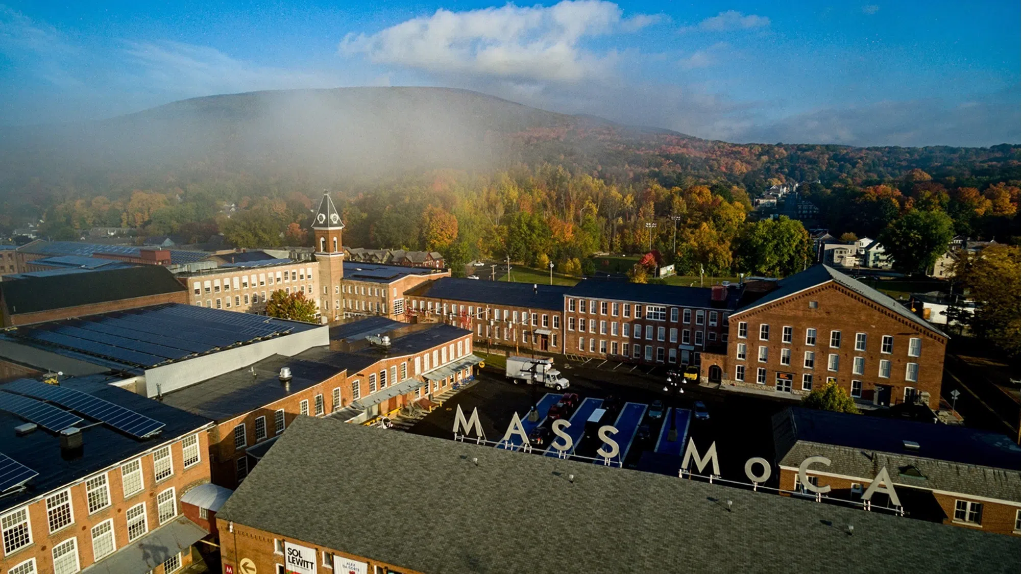 aerial of MASS MoCA sign above the red brick factory buildings that make up the museum