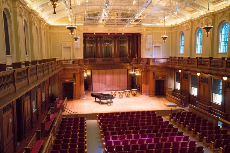 large performance hall with wooden accents and red seats