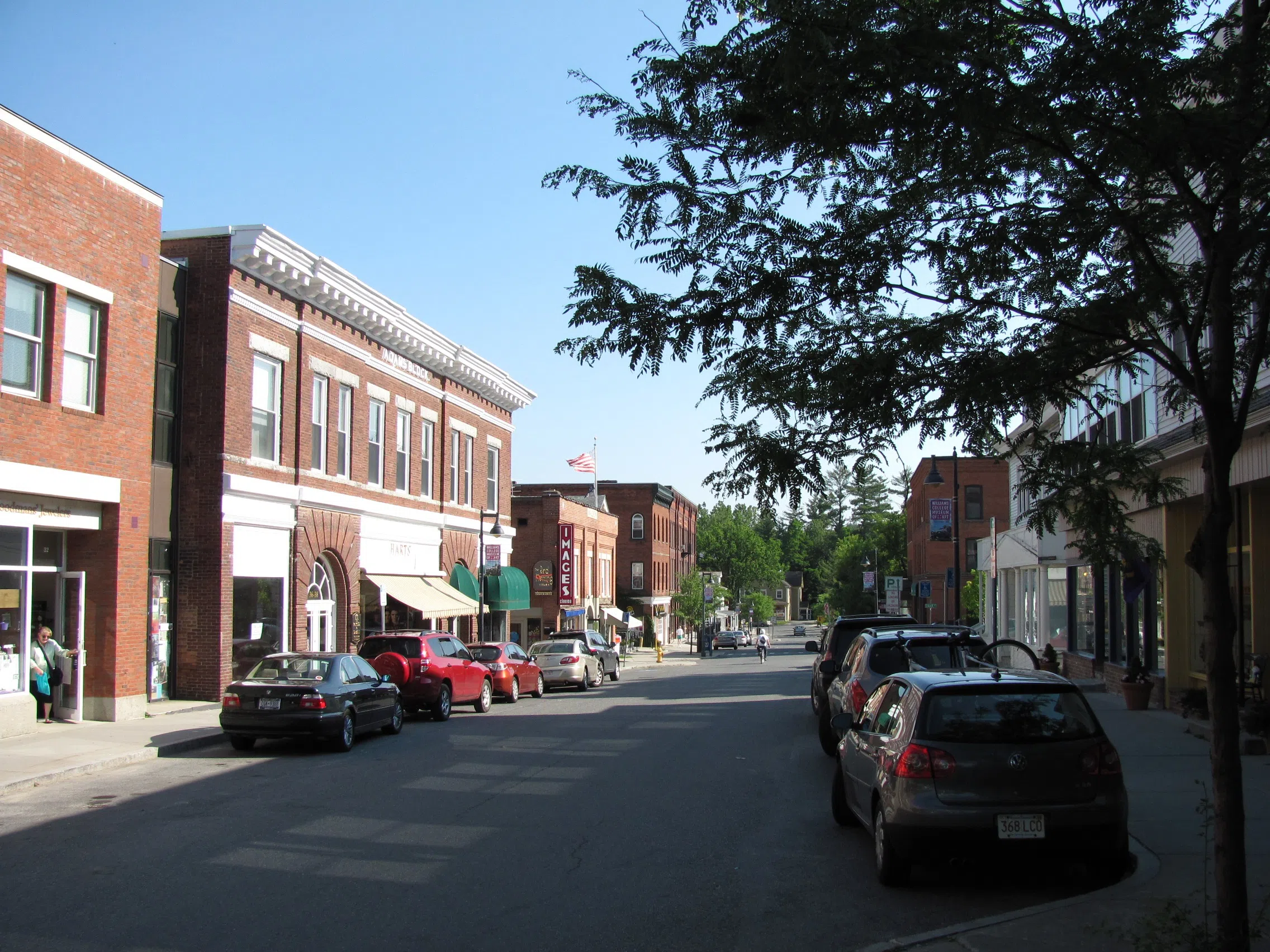 image of street with cars lining the road and red brick buildings