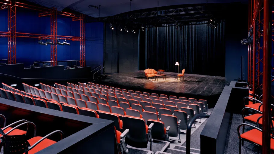 image behind seating facing a stage with a living room setup