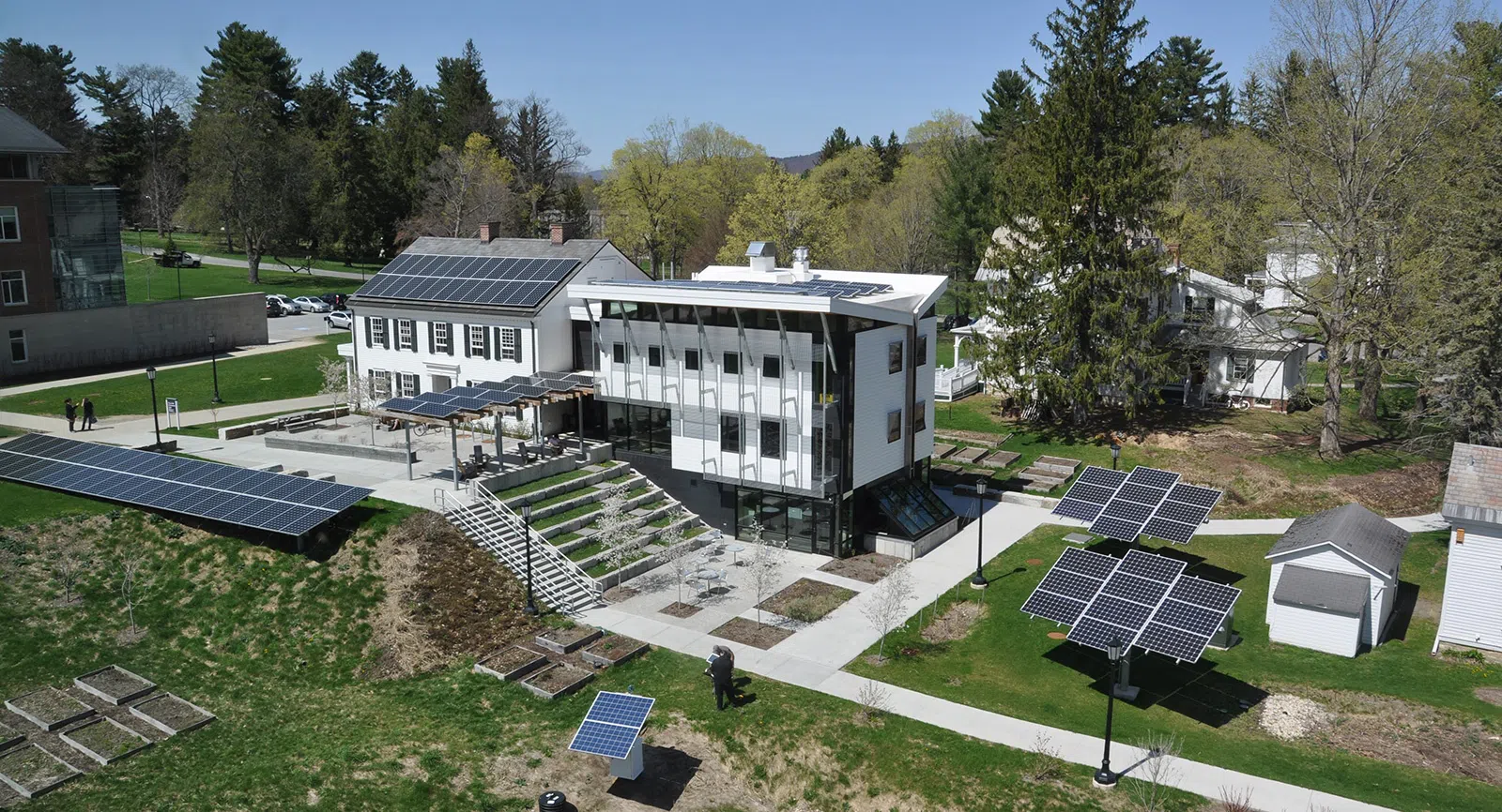 image of entire Zilkha Center, a white building with solar panels, and steps down to a garden