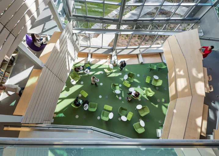 image from above of bottom floor of Sawyer, a study space with green chairs, tables, and floor