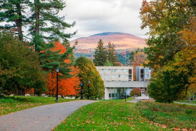 image of walkway to Mission Park, a concrete building surrounded by fall trees