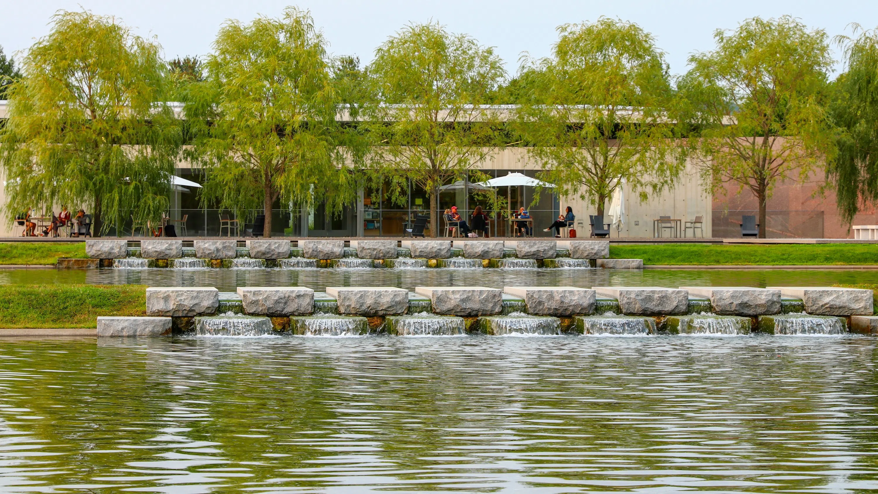 large reflecting pool in front of white museum building, with grass lawn and trees on sides