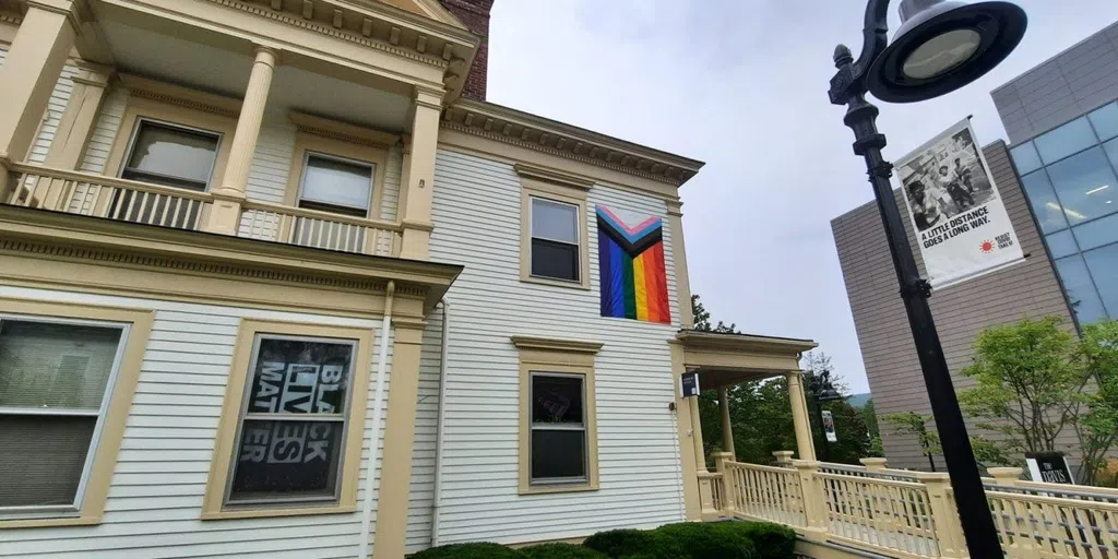 white two story house with pride flag and Black Lives Matter flag